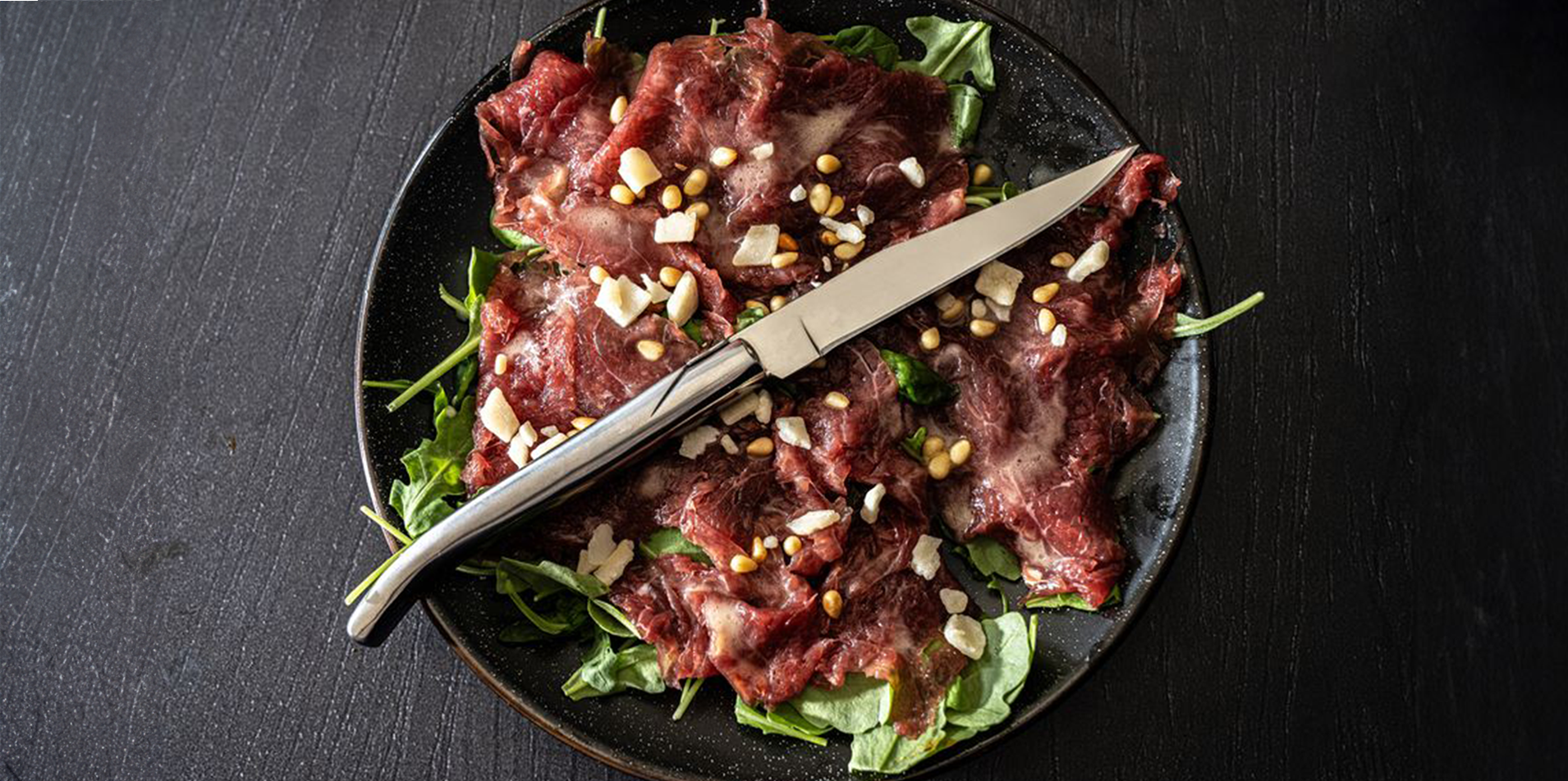 Laguiole homepage hero image knive on carpaccio board